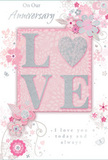 This image captures an anniversary card whose gentle colours and refined details mirror the quiet romance of an evening stroll through Colliers Wood. The card's background blends soft pastel pinks, pearly whites, and muted silvers, giving a serene, cloud-like atmosphere. At the centre, the word "LOVE" is prominently displayed in raised, glitter-lined letters, the textured surface sparkling subtly rather than glaring, like light resting on dewdrops. The "O" is rounded and welcoming, hinting at a heart shape without being overt. This central word sits within a blush-pink rectangle, lightly contrasting with the softer outer border. Surrounding it, delicate illustrated flowers and swirling vines spiral outward in graceful arcs, resembling the loose outline of a romantic bouquet. The blooms are shaded in blush and mauve with hints of grey and ivory, with fine silver details that shimmer gently, reminiscent of ribbons and foliage in a carefully arranged anniversary display. Scattered among the florals are tiny petals, looping curls, and subtle butterfly motifs that lend a feeling of movement, as though a soft breeze were stirring the design. At the top, the message "On Our Anniversary" appears in elegant script, while along the bottom, the phrase "I love you today and always" is printed in a more understated, complementary font, leaving generous white space so the eye can rest. The overall composition feels balanced and intimate, like a thoughtful card chosen to accompany same-day flower delivery to a home near Wandle Park or one of the quiet residential streets. It radiates lasting affection and appreciation, making it a gentle, heartfelt way to mark another year together.